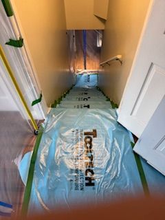 Un couloir avec des escaliers recouverts de plastique et de ruban adhésif.