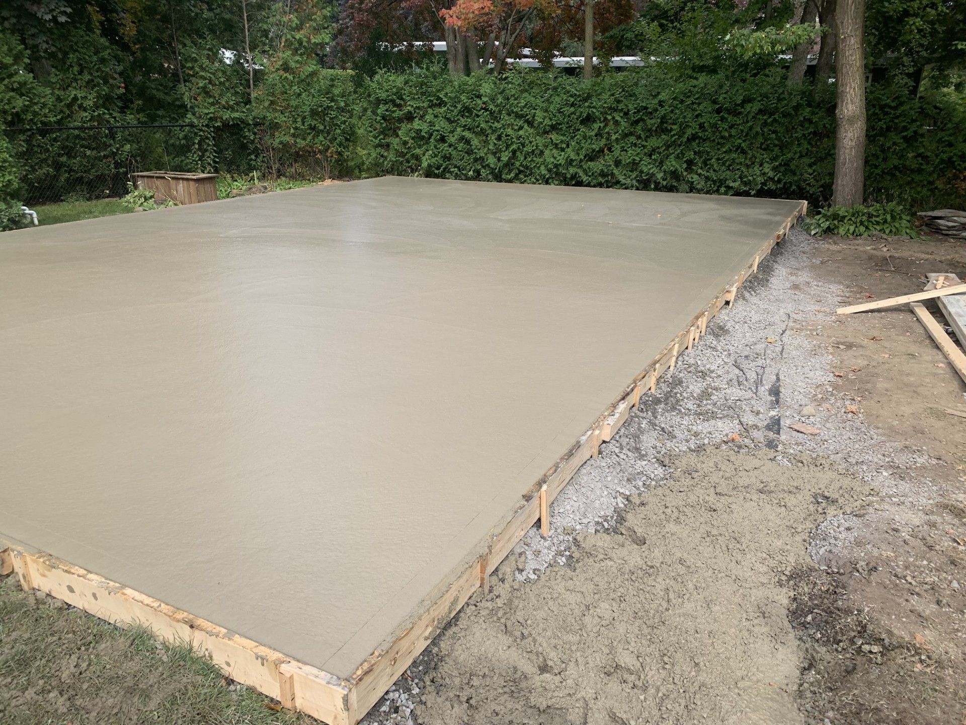 Un sol en béton est en cours de construction dans une cour arrière.