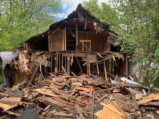 Une maison est en train d'être démolie et un tas de bois se trouve devant elle.
