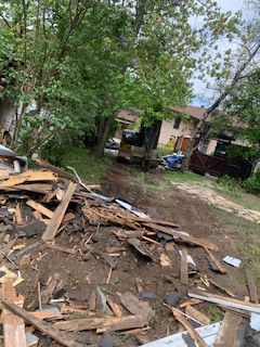 Un tas de bois est posé dans la terre devant une maison.