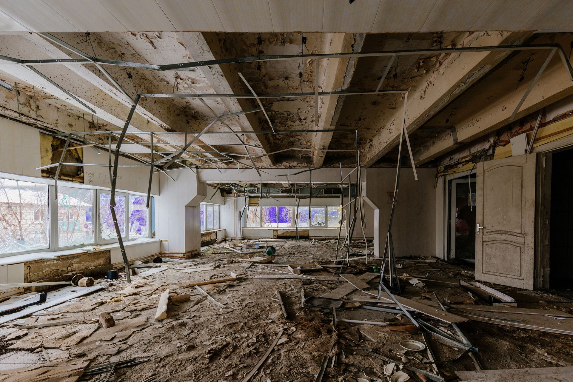 Une grande pièce dans un bâtiment abandonné avec beaucoup de gravats sur le sol.