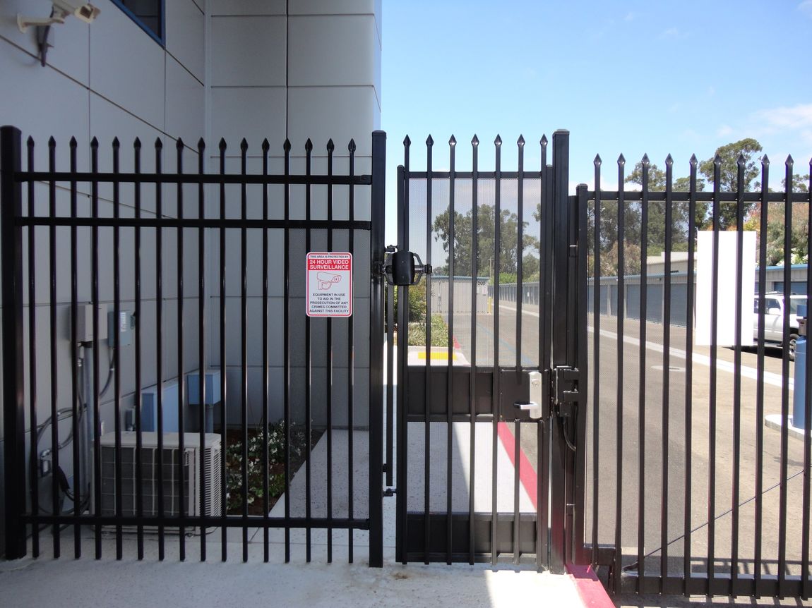 a black fence with a sign on it that says emergency exit only