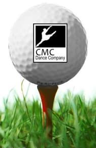 A white golf ball on a wooden tee in green grass, featuring a CMC Dance Company logo with a silhouette of a dancer.