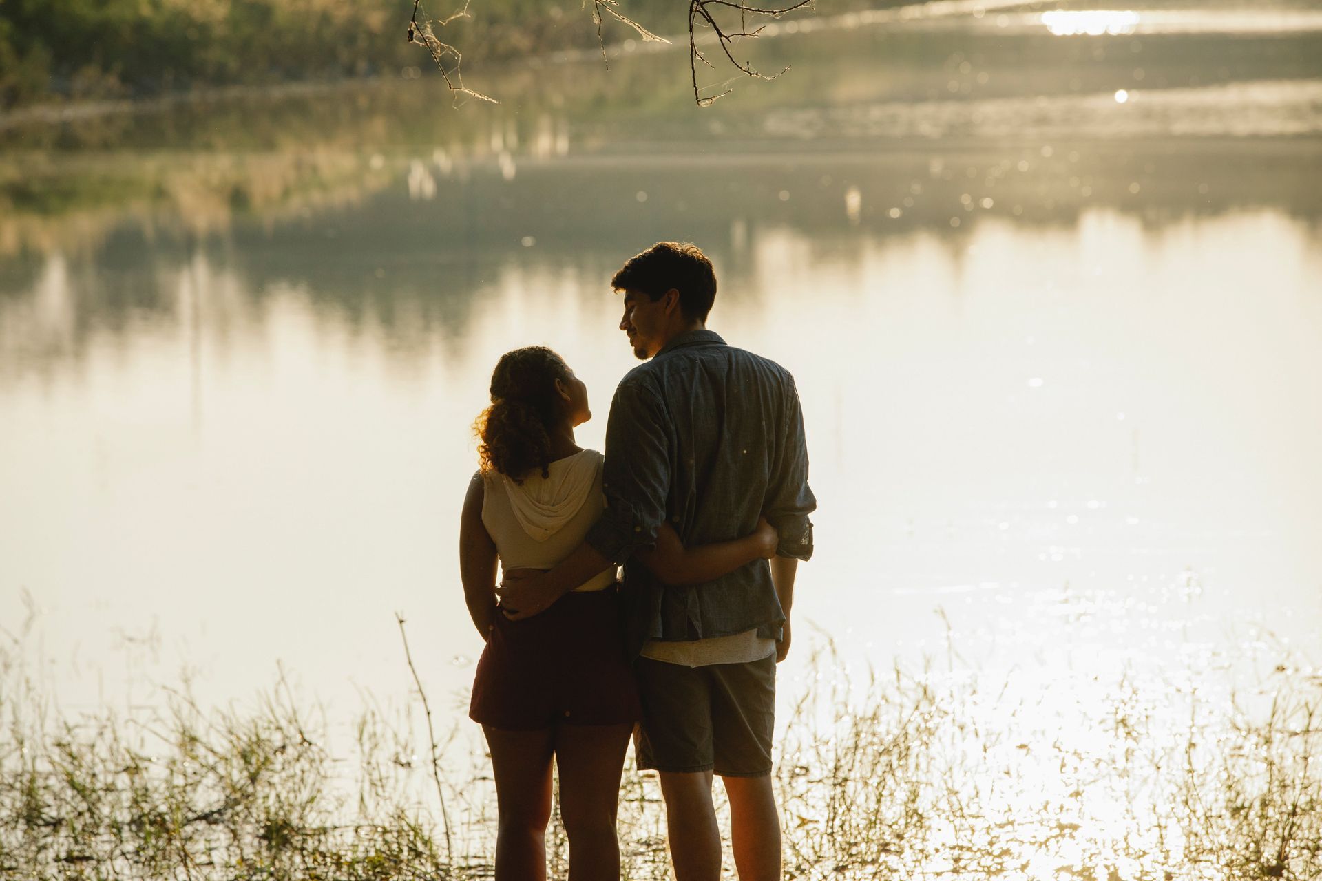 a man and a woman are standing next to a lake .