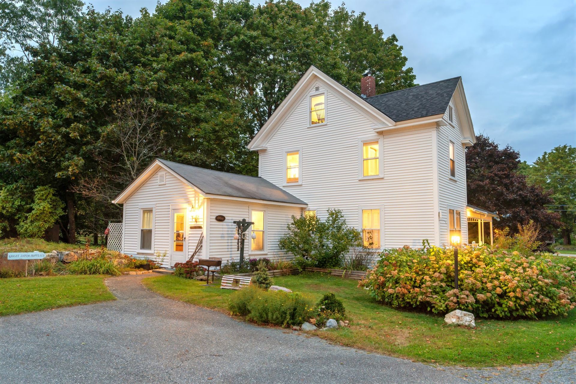 A white farmhouse with a small office connected to it.