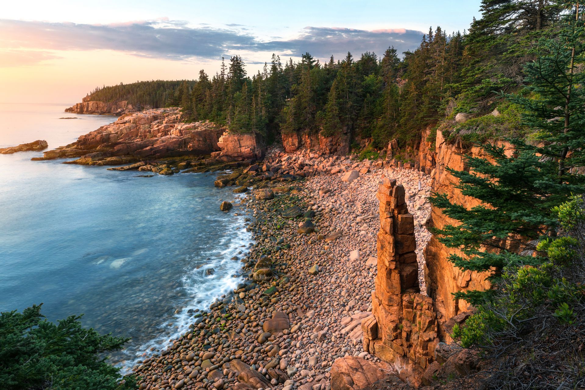 A cliff overlooking a body of water with a sunset in the background.