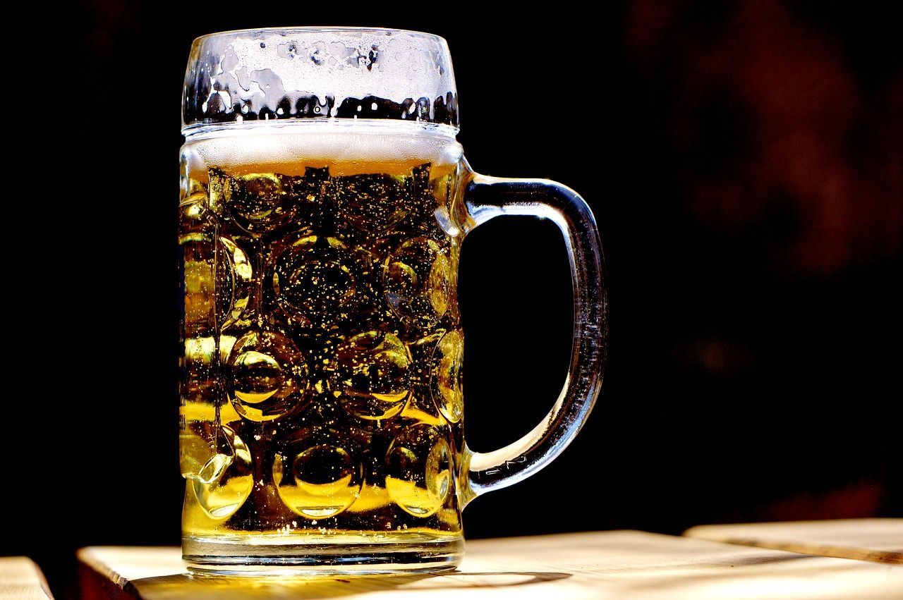 A glass of beer is sitting on a wooden table.