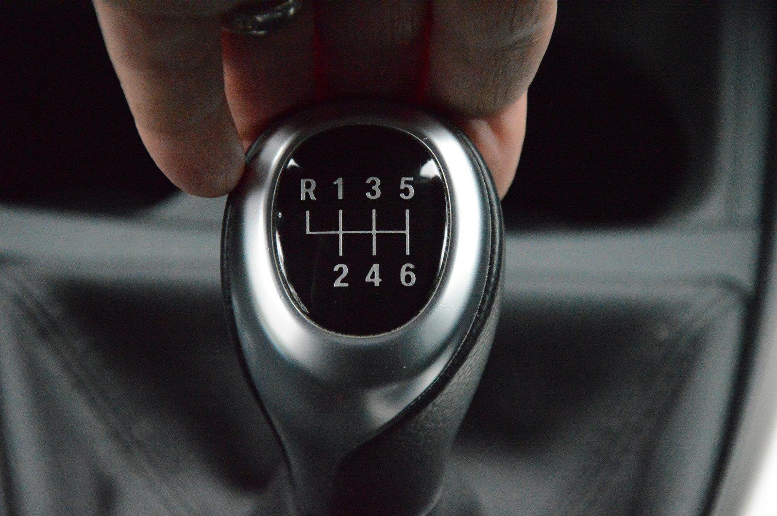 A person is holding a car shifter that says r135 4h 246