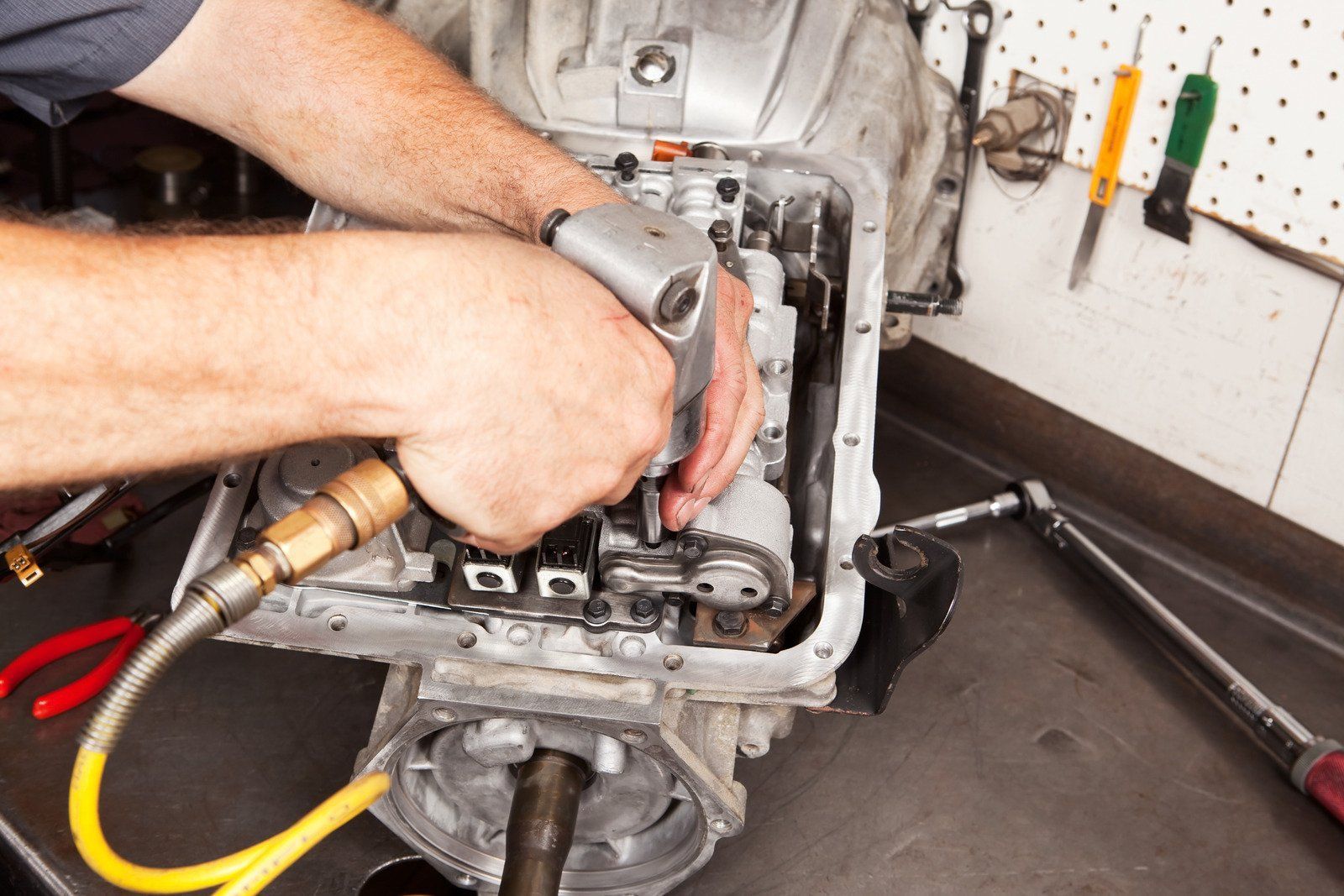 A man is working on a car engine with an air compressor.