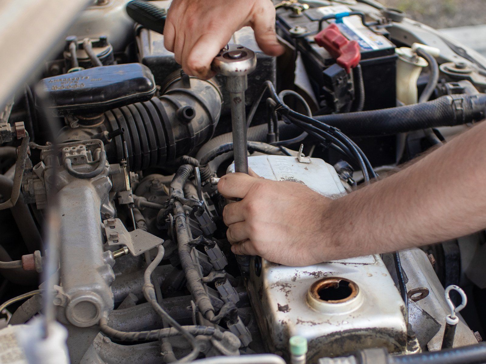 A man is working on a car engine with a wrench.