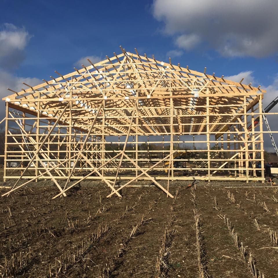 A large wooden structure is being built in a field.