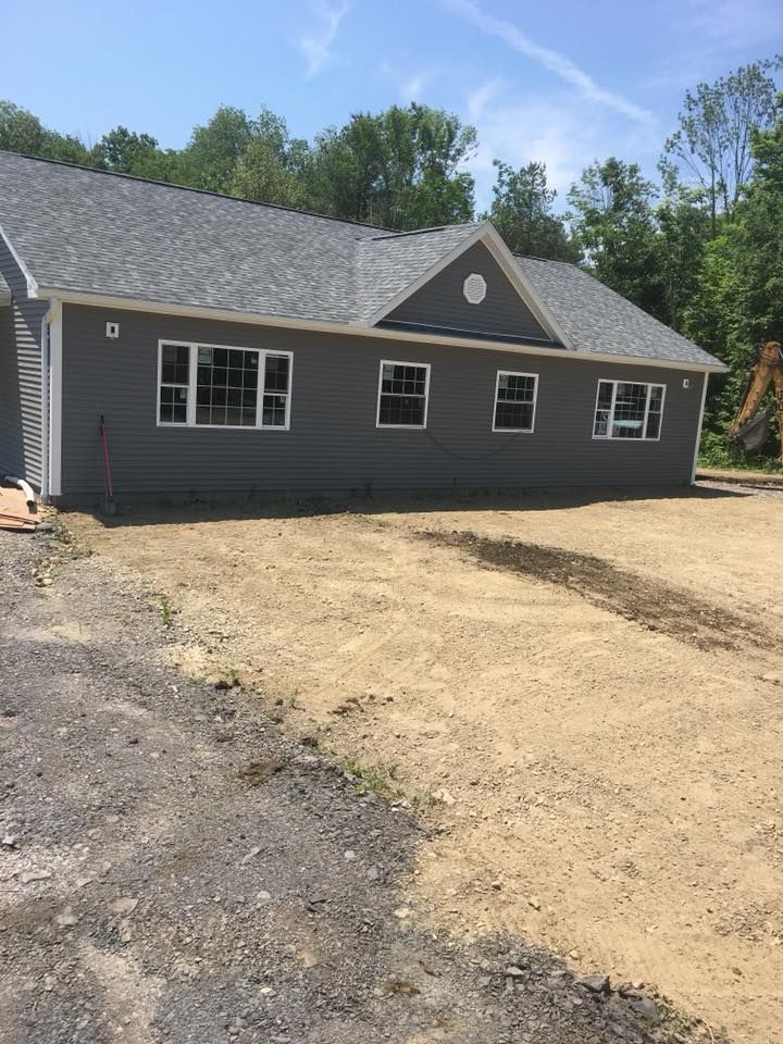 A house with a lot of windows is sitting on top of a dirt field.