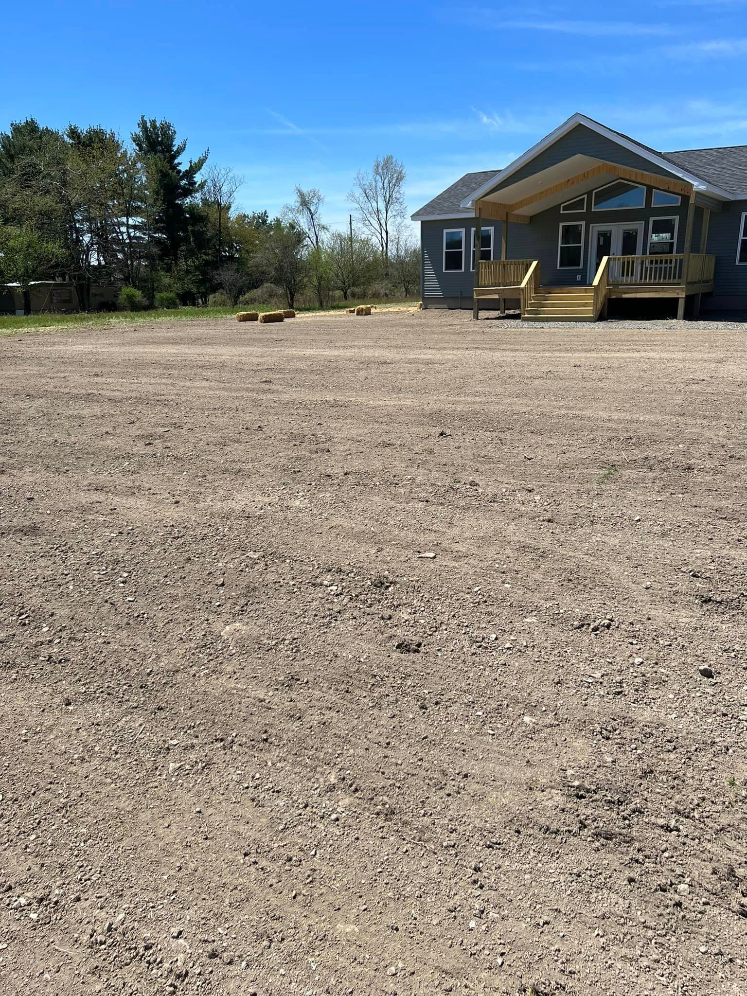 A house is sitting in the middle of a dirt field.