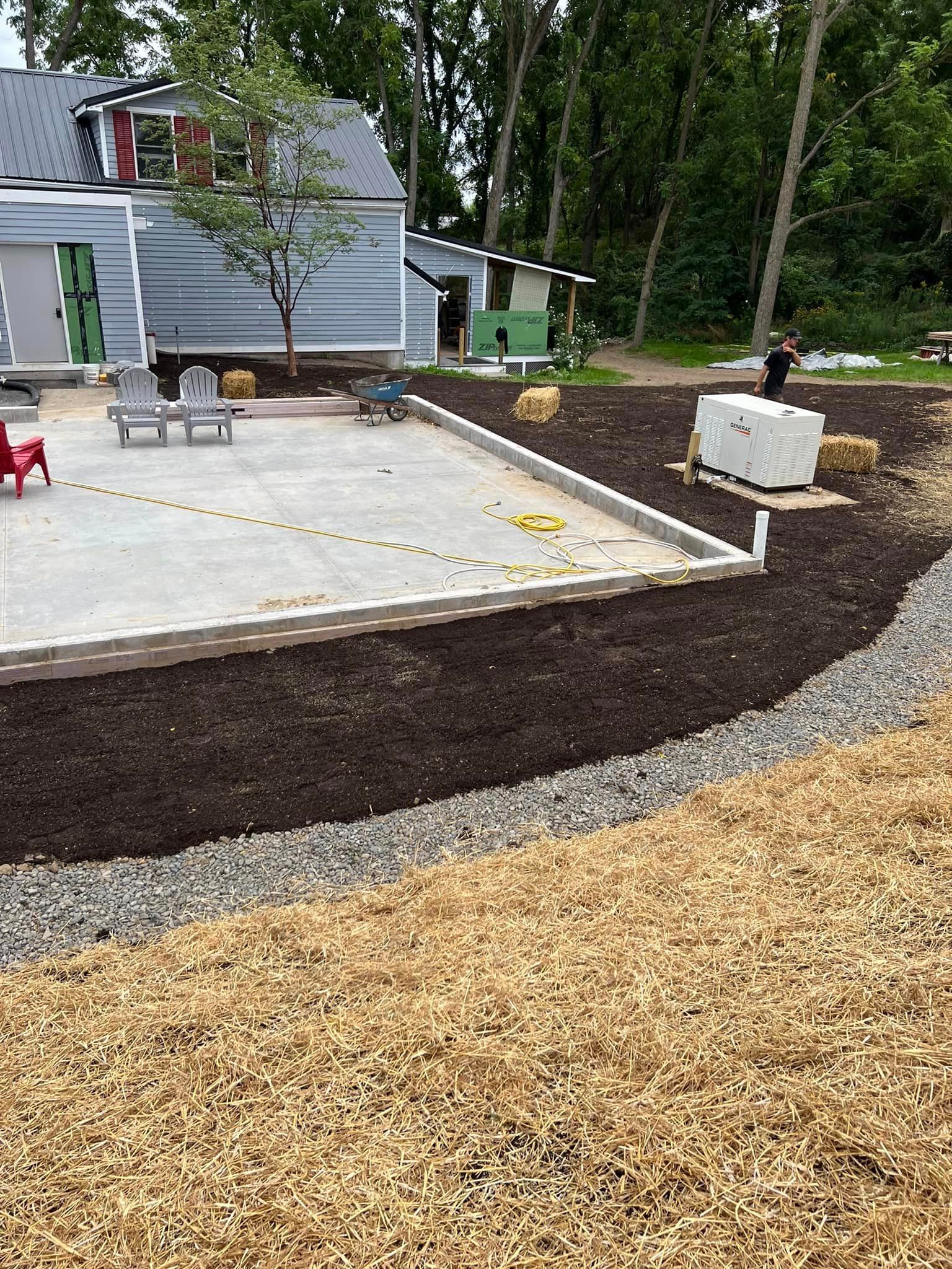 A concrete base for a house is being built in a backyard.
