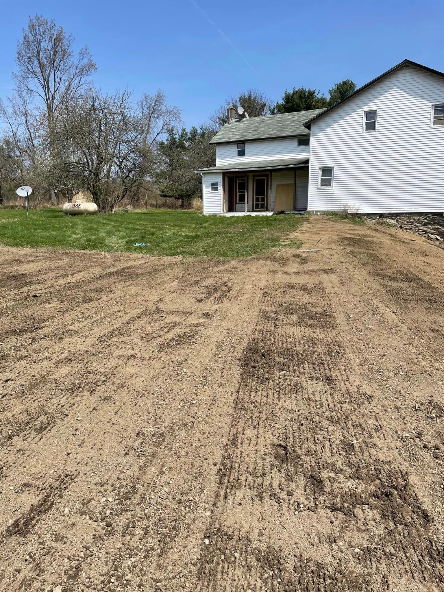 A white house is sitting in the middle of a dirt field.