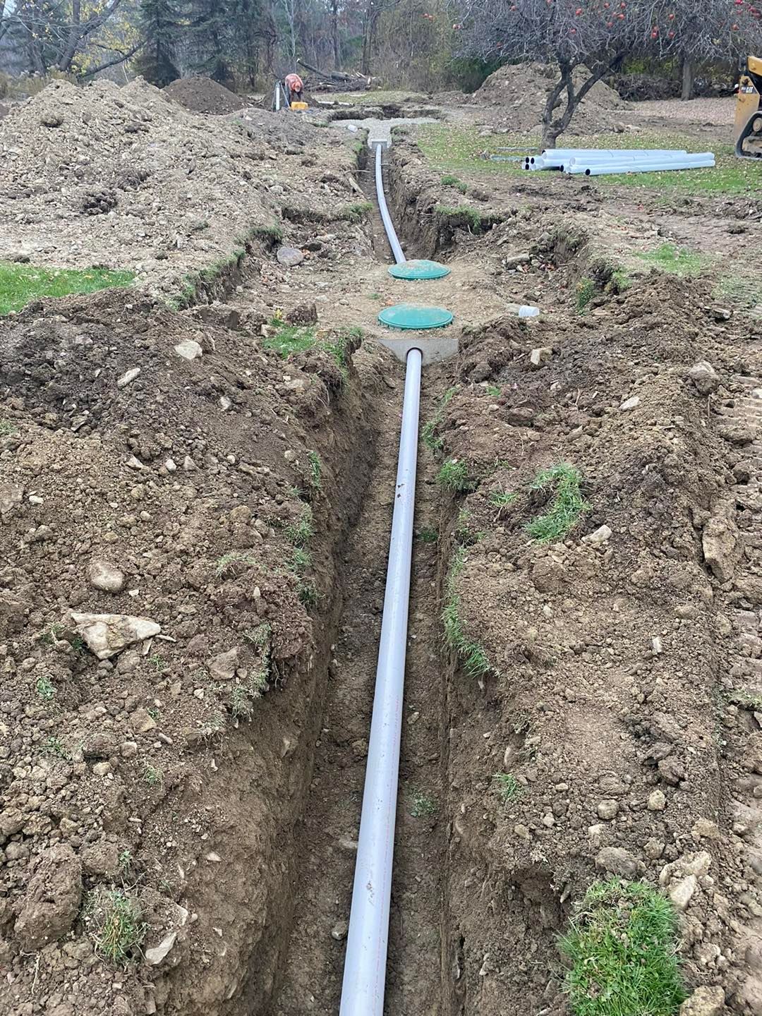 A pipe is being installed in the dirt in a field.