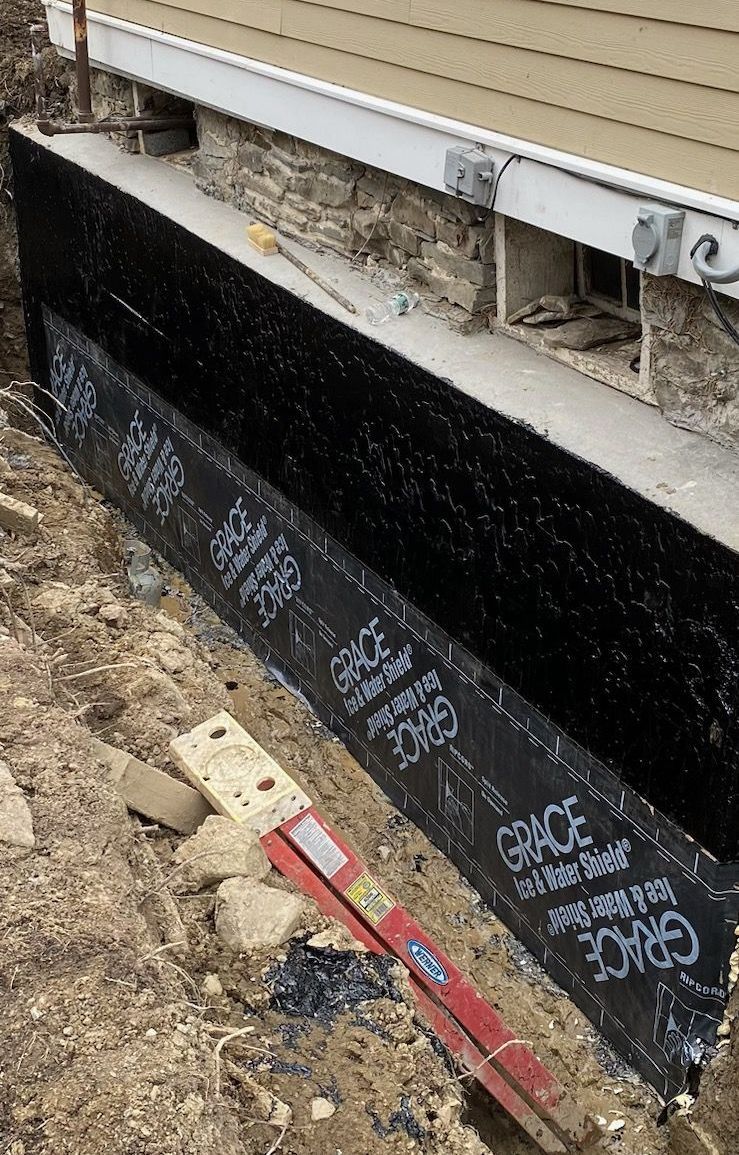 A black barrier is being installed on the side of a house.