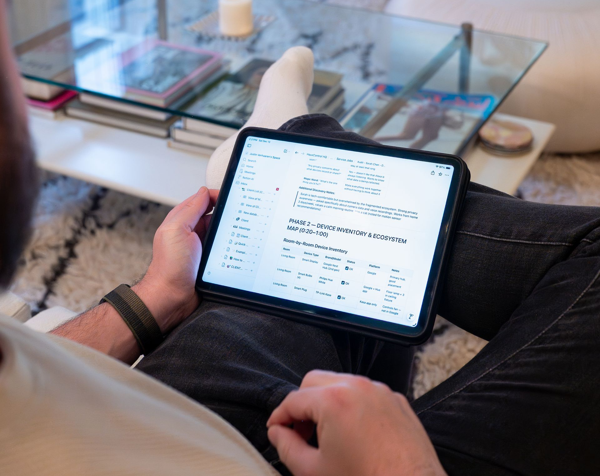 Person sitting, holding tablet with document on lap. Living room setting with coffee table.