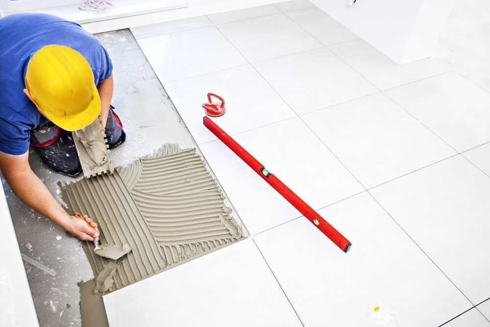 A Man is Cutting a Piece of Concrete With a Saw — ASpect Wall & Floor Tiling in Charmhaven, NSW