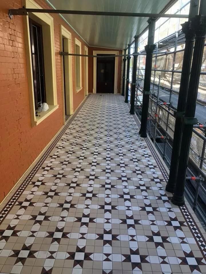A Long Hallway With a Tiled Floor and a Brick Wall — ASpect Wall & Floor Tiling in Erina, NSW