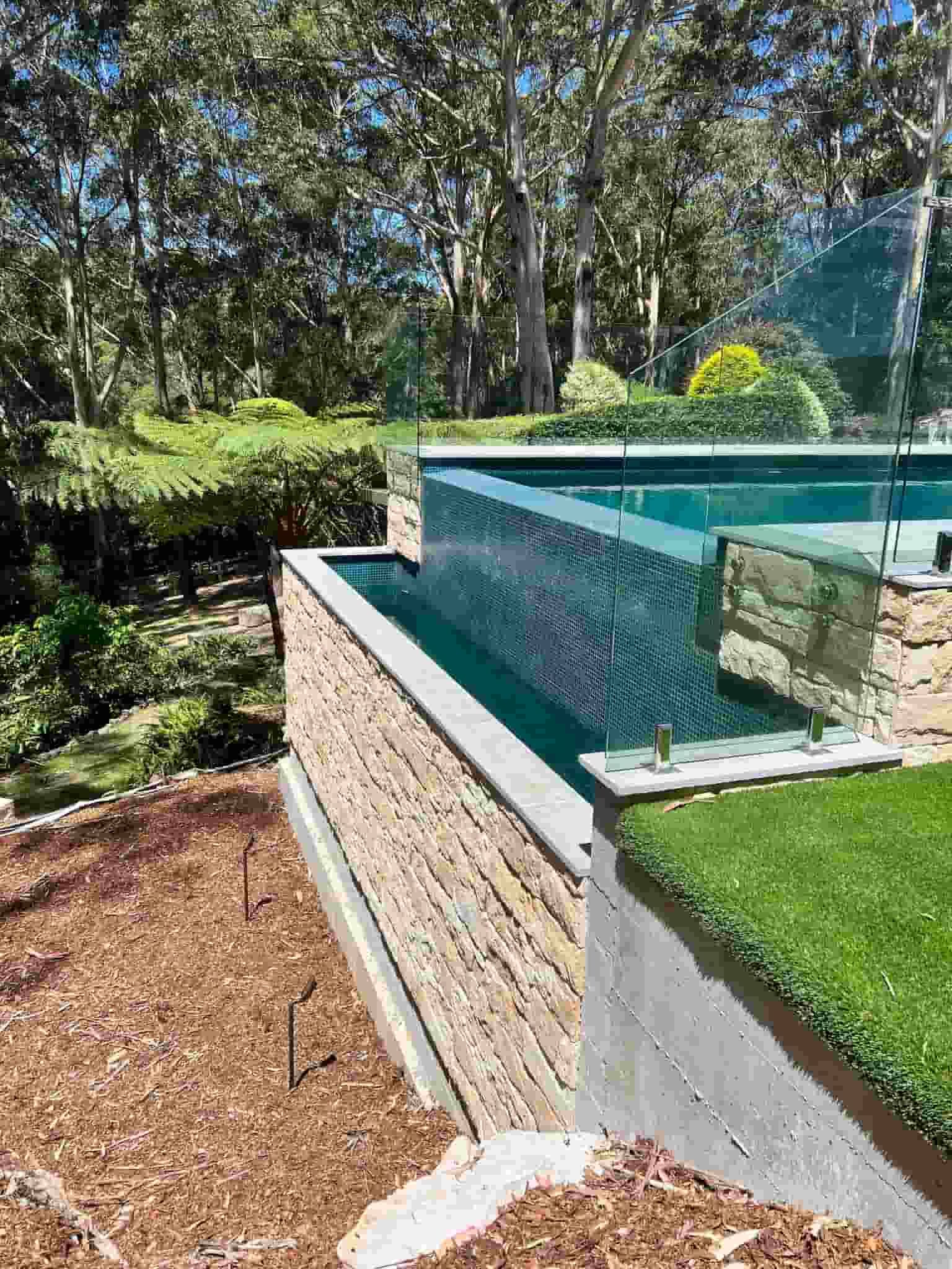 A Large Swimming Pool Surrounded by Trees in a Backyard 
— ASpect Wall & Floor Tiling in Charmhaven, NSW