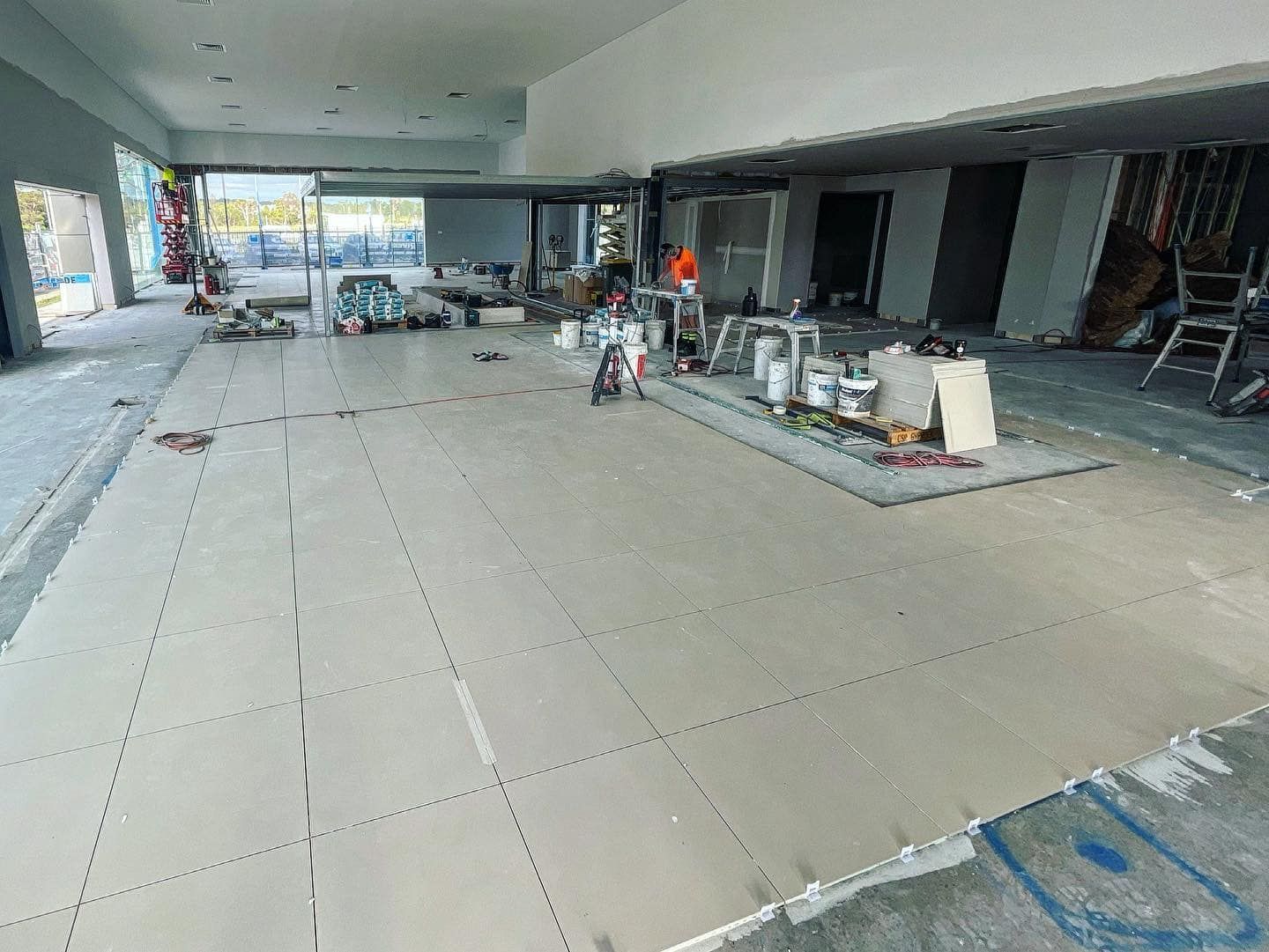 A Vacuum Cleaner is Sitting on the Floor of an Empty Room Next to a Red and White Tape — ASpect Wall & Floor Tiling in Charmhaven, NSW