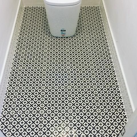 A Toilet is Sitting on a Black and White Tiled Floor in a Bathroom — ASpect Wall & Floor Tiling in Charmhaven, NSW