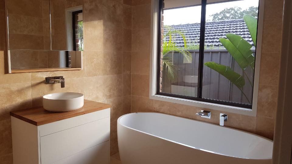 A Bathroom With a Tub , Sink , Mirror and Window — ASpect Wall & Floor Tiling in Forster, NSW