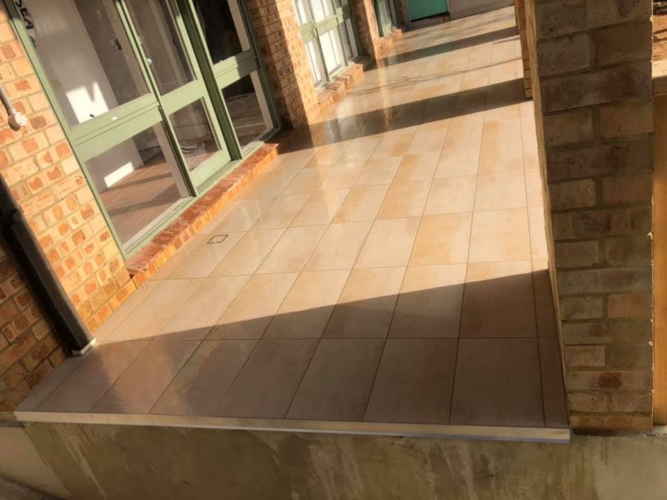A Brick Building With a Tiled Floor in Front of It — ASpect Wall & Floor Tiling in Charmhaven, NSW