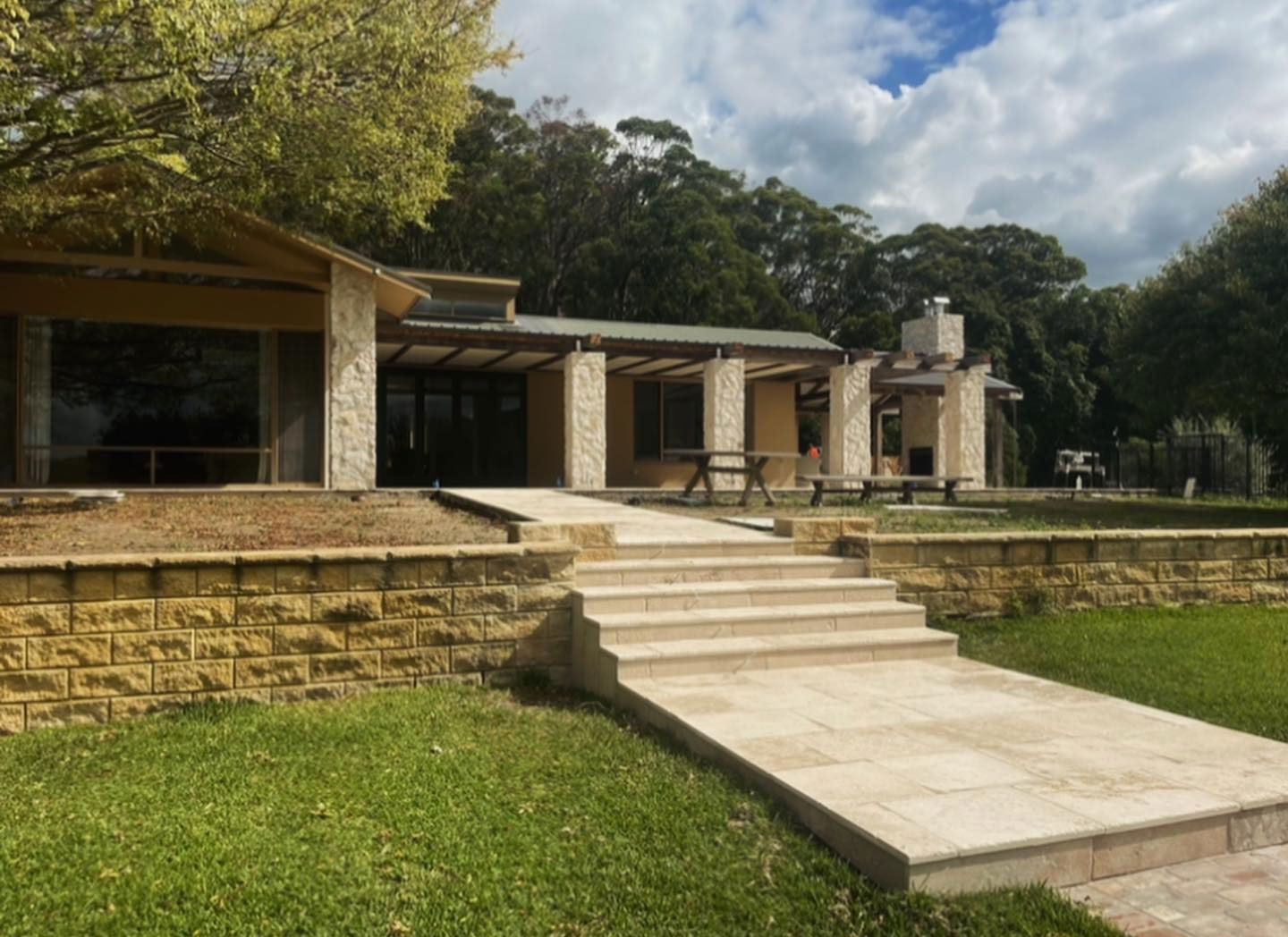 A House With Stairs Leading Up to It is Surrounded by Grass and Trees — ASpect Wall & Floor Tiling in Charmhaven, NSW