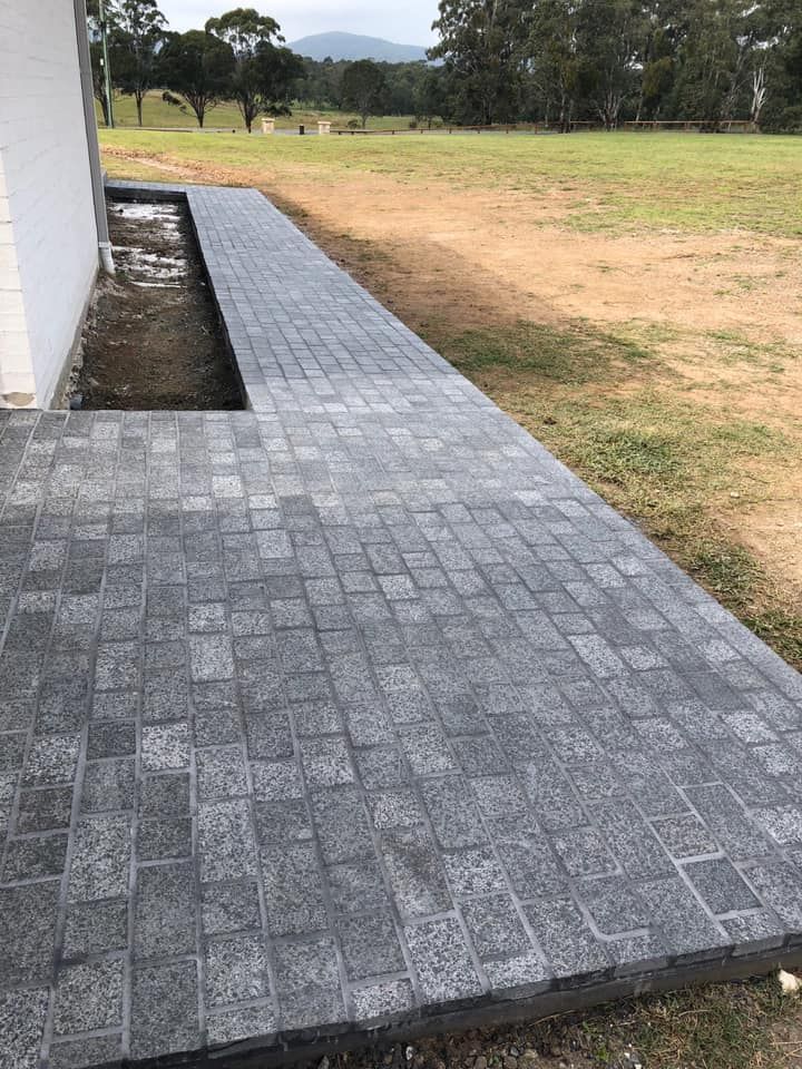 A Brick Walkway Leading to a House in a Field — ASpect Wall & Floor Tiling in Lake Macquarie, NSW