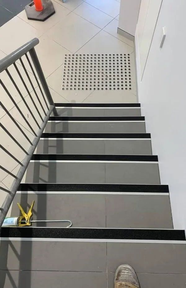 A Person is Standing on a Set of Stairs With Black Steps — ASpect Wall & Floor Tiling in Charmhaven, NSW