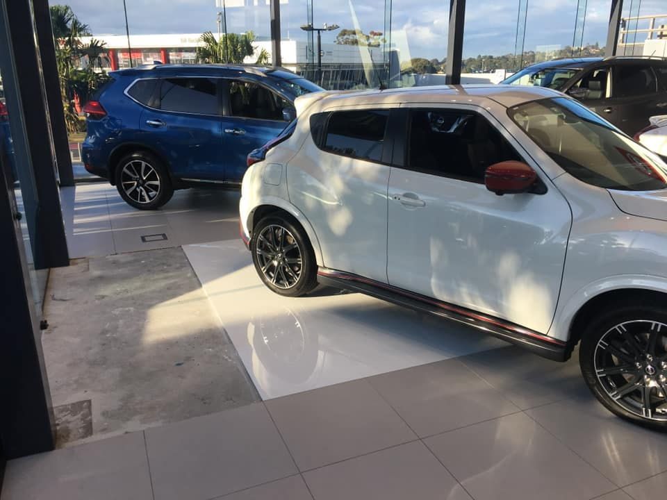 A White Car is Parked Next to a Blue SUV in a Showroom — ASpect Wall & Floor Tiling in Charmhaven, NSW