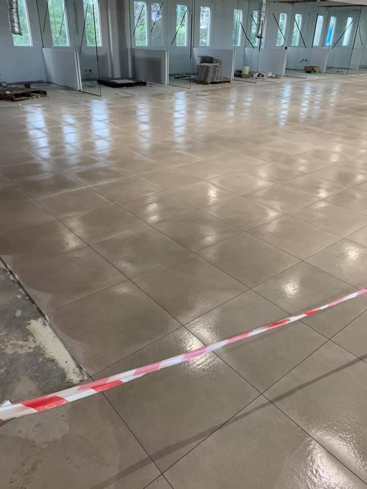 A Large Empty Room With a Tiled Floor and a Red and White Tape — ASpect Wall & Floor Tiling in Wyong, NSW