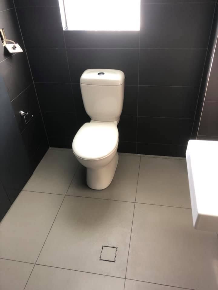 A Toilet is Sitting on a Tiled Floor in a Bathroom — ASpect Wall & Floor Tiling in Charmhaven, NSW