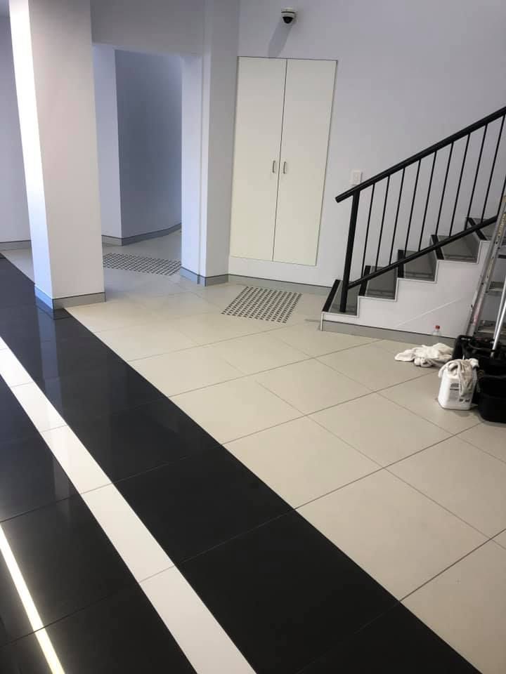 A Black and White Floor With a Staircase in the Background — ASpect Wall & Floor Tiling in Newcastle, NSW