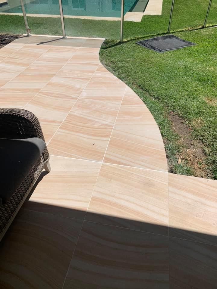 A Patio With a Chair and a Wicker Chair Next to a Pool — ASpect Wall & Floor Tiling in Hunter Valley, NSW