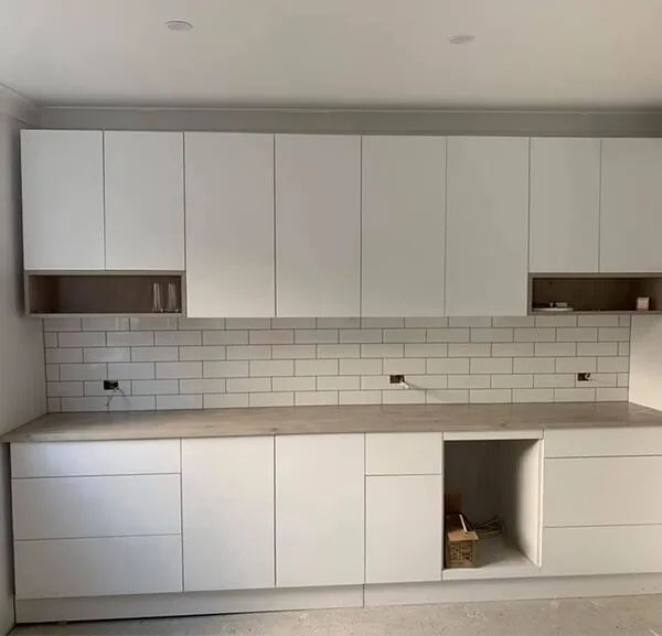 A Kitchen With White Cabinets and a Brick Wall — ASpect Wall & Floor Tiling in Forster, NSW
