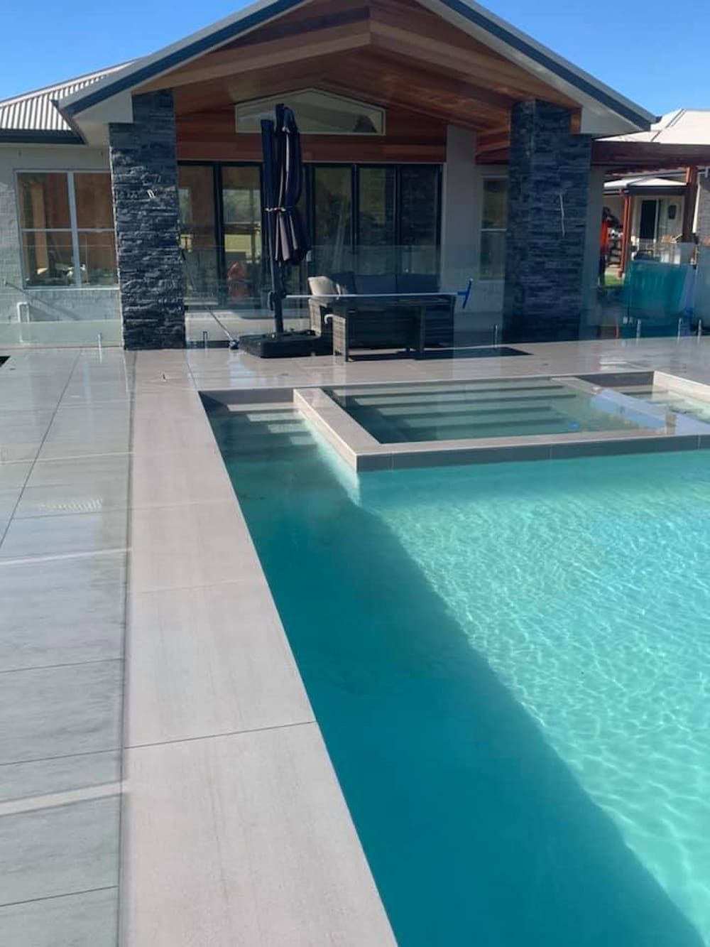 There Is A Large Swimming Pool In Front Of A House  — ASpect Wall & Floor Tiling in Forster, NSW