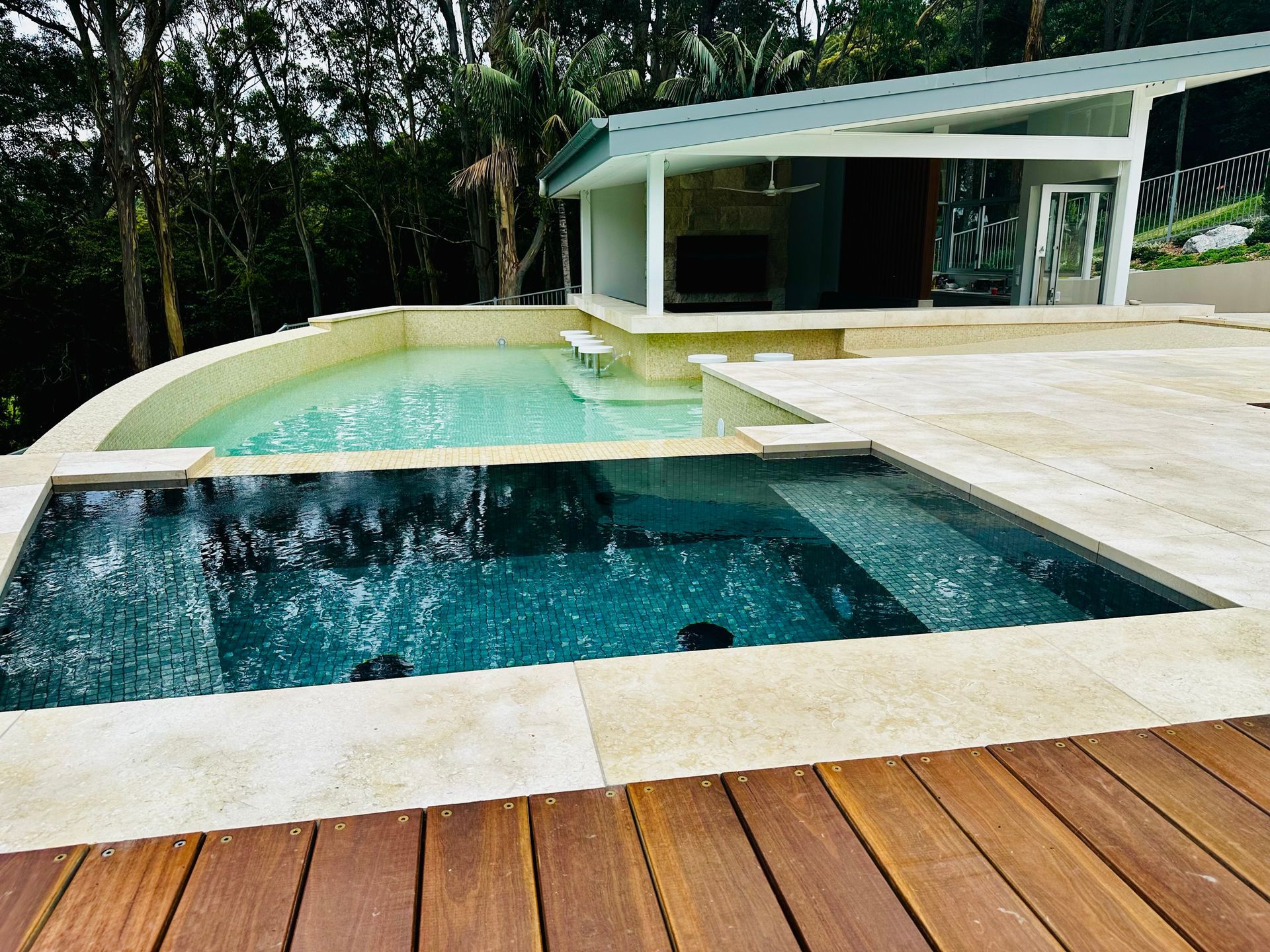 A Large Swimming Pool is Surrounded by a Wooden Deck β ASpect Wall & Floor Tiling in Charmhaven, NSW