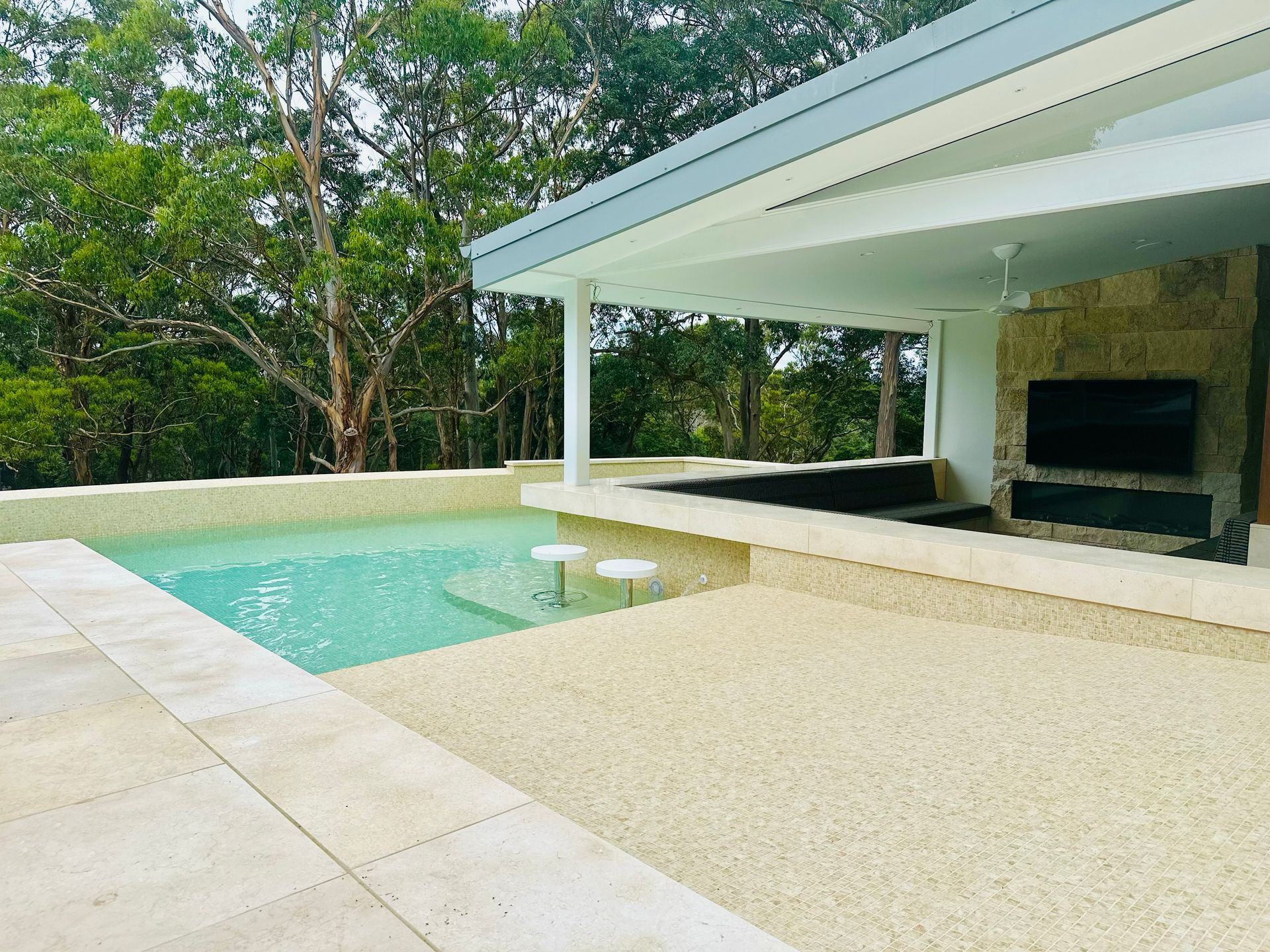 A Large Swimming Pool is Surrounded by Trees and a Building β ASpect Wall & Floor Tiling in Charmhaven, NSW