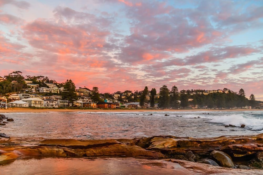 A Sunset Over a Beach With a City in the Background — ASpect Wall & Floor Tiling in Charmhaven, NSW
