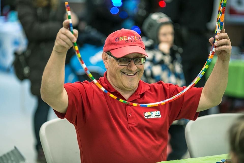 A group of children are sitting at a table with their hands in the air.