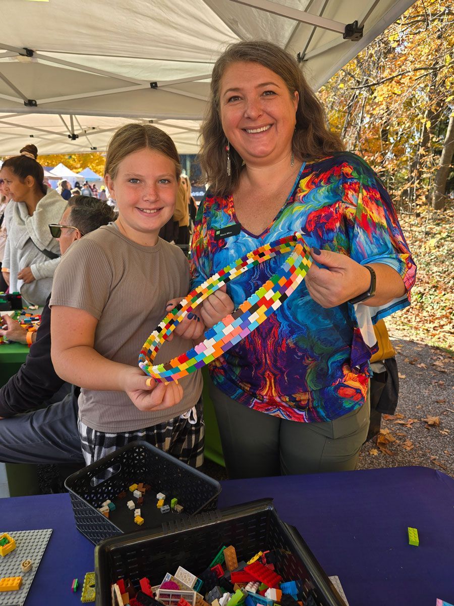 A woman and a girl are holding a piece of lego.
