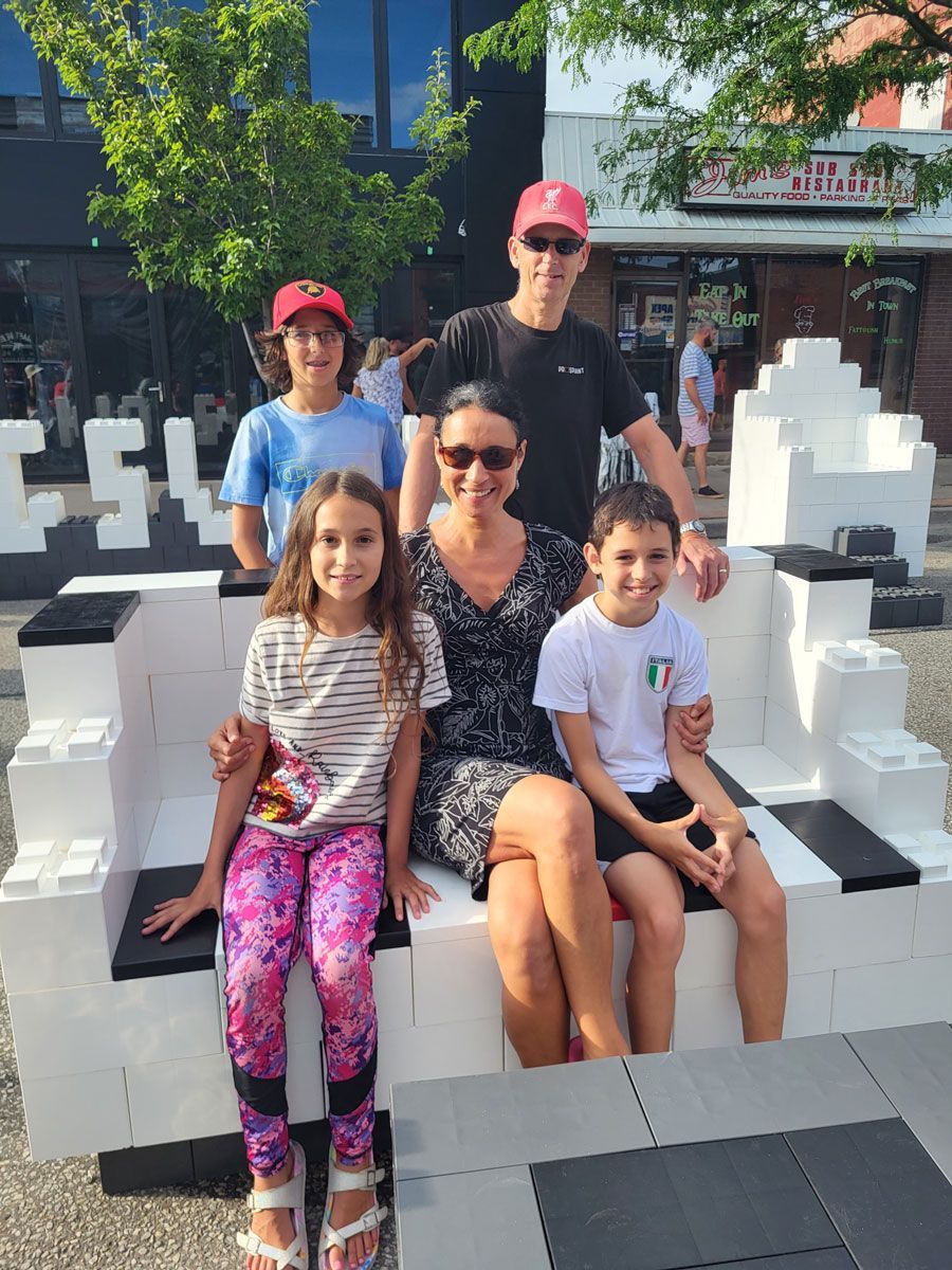 A family is sitting on a bench made of lego blocks.