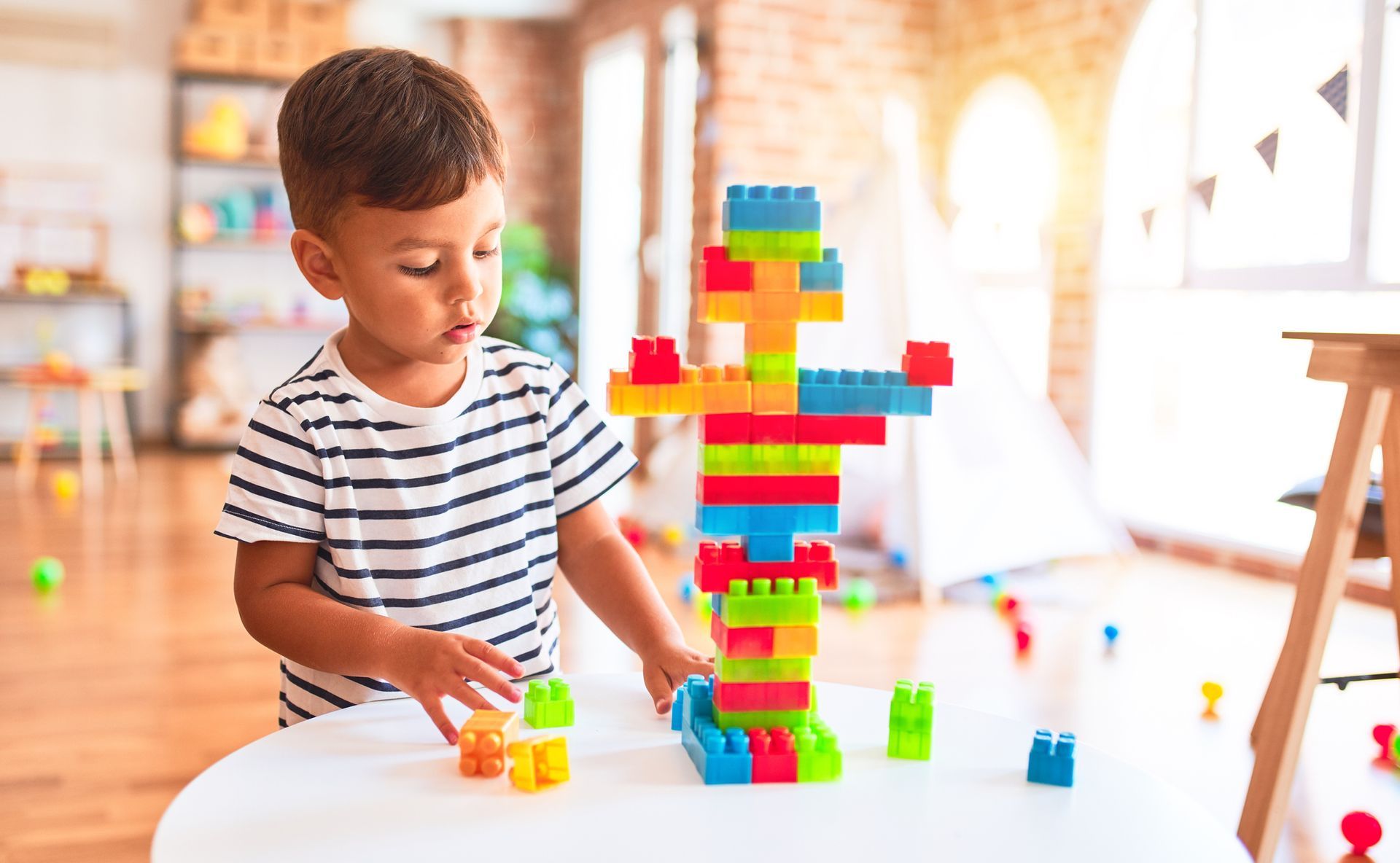 A young boy is playing with colorful lego blocks at a table.