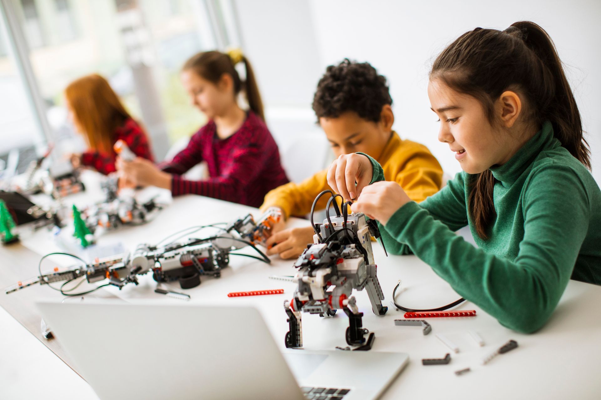 A group of children are sitting at a table building a robot.