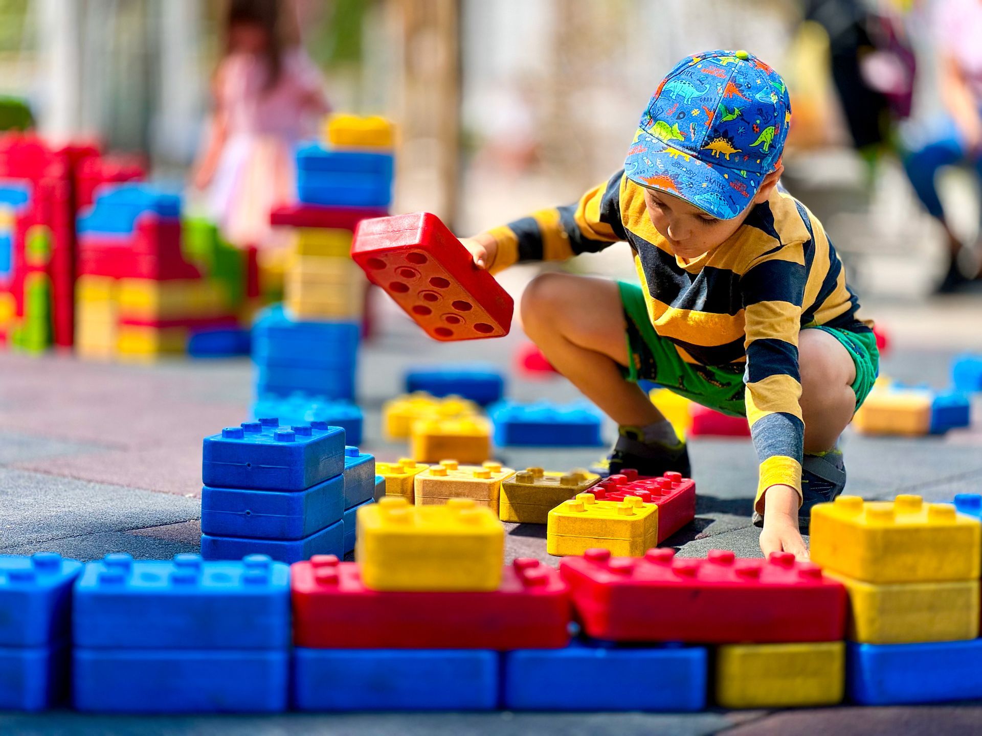 A young boy is playing with colorful lego blocks in a park.