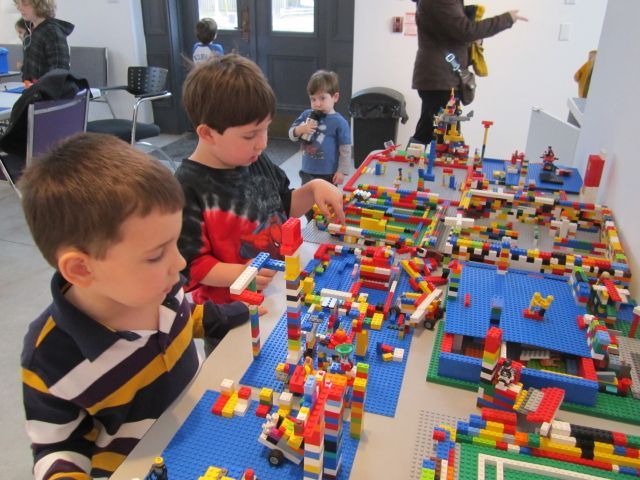 Two young boys are playing with lego on a table