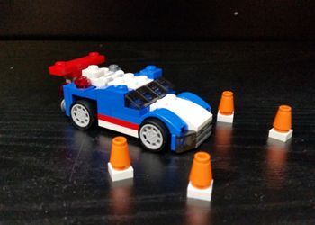 A blue and white lego car is surrounded by orange cones